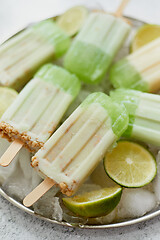 Image showing Summer refreshing homemade lime popsicles with chipped ice over stone background