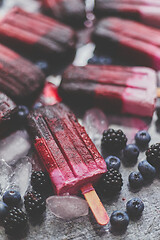 Image showing Homemade blackberry and cream ice-creams or popsicles with frozen berries on black slate tray