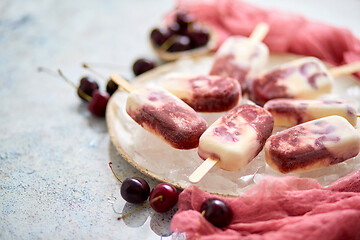 Image showing Fresh cream and cherry homemade popsicles placed on white ceramic plate with fruits and textile