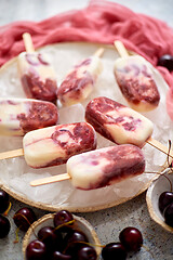 Image showing Fresh cream and cherry homemade popsicles placed on white ceramic plate with fruits and textile