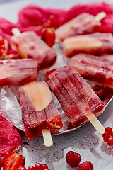 Image showing Strawberry raspberry apple and red currant ice cream popsicles in metal tray with ice cubes