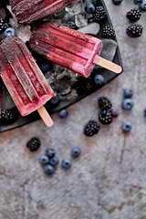 Image showing Forrest fruit ice cream on stick. Homemade healthy vegan snack. Placed on plate with ice