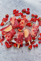 Image showing Homemade raspberry, strawberry, apple and currant popsicles on metal plate with ice assorted berries