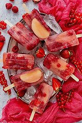 Image showing Homemade raspberry, strawberry, apple and currant popsicles on metal plate with ice assorted berries