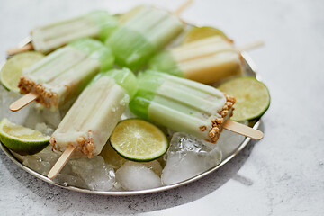 Image showing Summer refreshing homemade lime popsicles with chipped ice over stone background