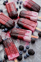 Image showing Homemade blackberry and cream ice-creams or popsicles with frozen berries on black slate tray