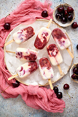 Image showing Fresh cream and cherry homemade popsicles placed on white ceramic plate with fruits and textile