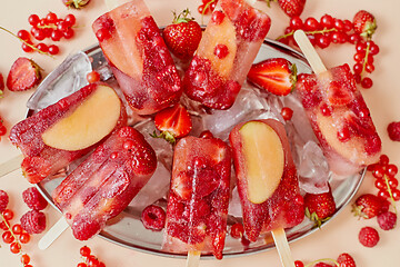 Image showing Strawberry raspberry apple and red currant ice cream popsicles in metal tray with ice cubes