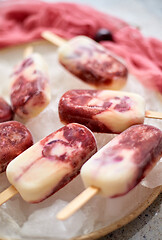 Image showing Fresh cream and cherry homemade popsicles placed on white ceramic plate with fruits and textile