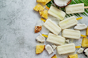 Image showing Homemade pineapple coconut popsicles on stone background. Summer food concept with copy space