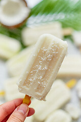 Image showing Closeup on hand holding homemade pineapple coconut popsicle. Summer food concept.