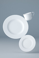 Image showing Mockup of two white plates and a cup levitating on blue background