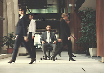 Image showing business man sitting in office chair, people group  passing by