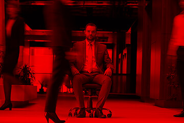 Image showing business man sitting in office chair, people group  passing by