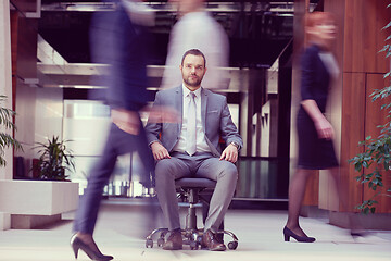 Image showing business man sitting in office chair, people group  passing by