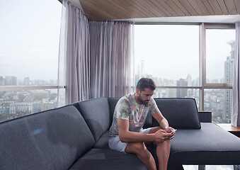 Image showing young casual man using a mobile phone at home