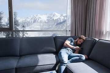 Image showing young casual man using a mobile phone at home