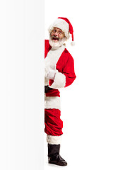 Image showing Happy Santa Claus pointing on blank advertisement banner background with copy space. Smiling Santa Claus pointing in white blank sign