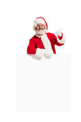 Image showing Happy Santa Claus pointing on blank advertisement banner background with copy space. Smiling Santa Claus pointing in white blank sign