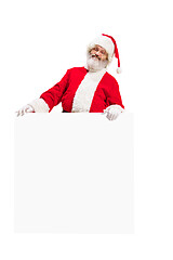 Image showing Happy Santa Claus pointing on blank advertisement banner background with copy space. Smiling Santa Claus pointing in white blank sign