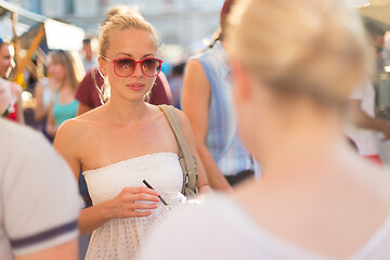 Image showing It is nice to see you. It has been a while. Two happy young female friends enjoying a conversation on urban food market at random after work encounter. Pleasant free time socializing