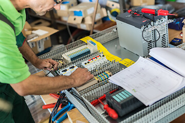 Image showing Electrician assembling industrial electric cabinet in workshop