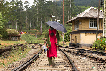 Image showing Woman wearing traditional sari and black umbrella walking on railway tracks in Sri Lanka.