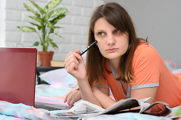 Image showing The girl thought while lying in front of a laptop in search of work