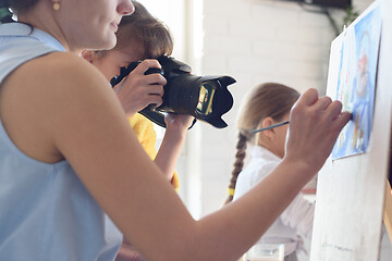 Image showing Girl takes pictures of how the artist works