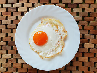 Image showing Fried egg on a white plate on a wooden background