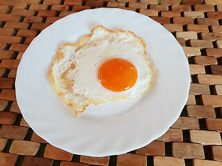 Image showing Fried egg on a white plate on a wooden background