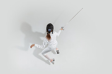 Image showing Teen girl in fencing costume with sword in hand isolated on white background, top view