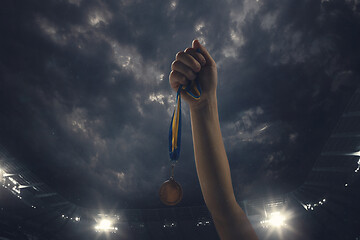 Image showing Award of victory, male hands tightening the medal of winners against cloudy dark sky