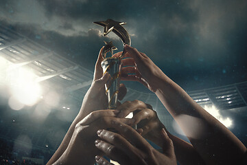 Image showing Award of victory, male hands tightening the cup of winners against cloudy dark sky