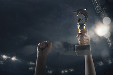 Image showing Award of victory, male hands tightening the cup of winners against cloudy dark sky