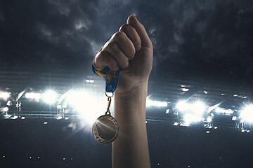 Image showing Award of victory, male hands tightening the medal of winners against cloudy dark sky