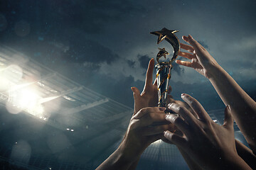 Image showing Award of victory, male hands tightening the cup of winners against cloudy dark sky