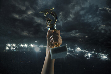 Image showing Award of victory, male hands tightening the cup of winners against cloudy dark sky