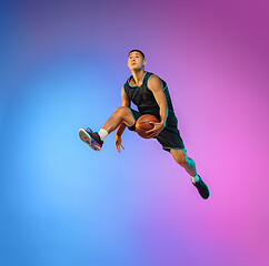 Image showing Young basketball player in motion on gradient studio background in neon light