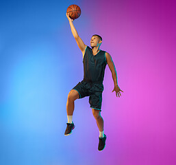 Image showing Young basketball player in motion on gradient studio background in neon light