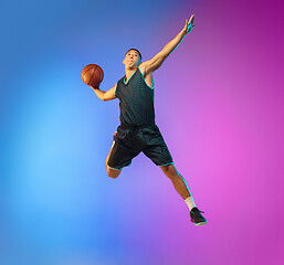 Image showing Young basketball player in motion on gradient studio background in neon light