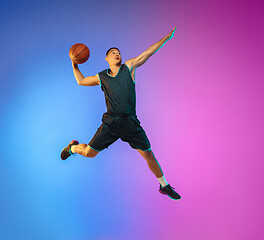 Image showing Young basketball player in motion on gradient studio background in neon light