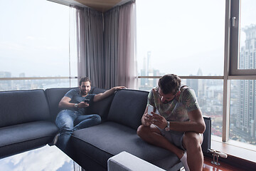 Image showing two young men using a mobile phones  at home