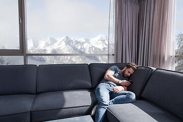 Image showing young casual man using a mobile phone at home