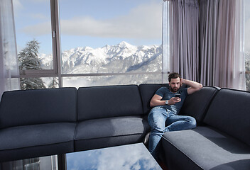 Image showing young casual man using a mobile phone at home