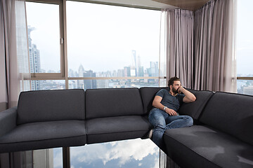 Image showing young casual man using a mobile phone at home