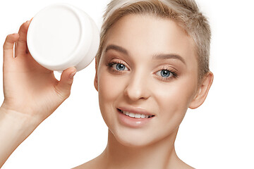 Image showing Cute girl preparing to start her day. She is applying moisturizer cream on face.