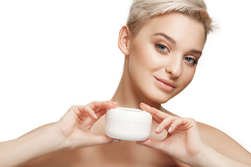 Image showing Cute girl preparing to start her day. She is applying moisturizer cream on face.