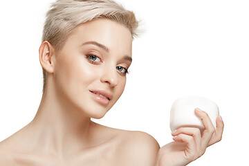 Image showing Cute girl preparing to start her day. She is applying moisturizer cream on face.