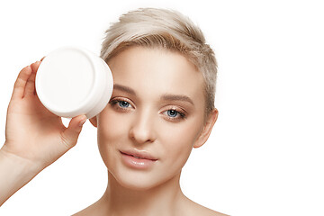 Image showing Cute girl preparing to start her day. She is applying moisturizer cream on face.